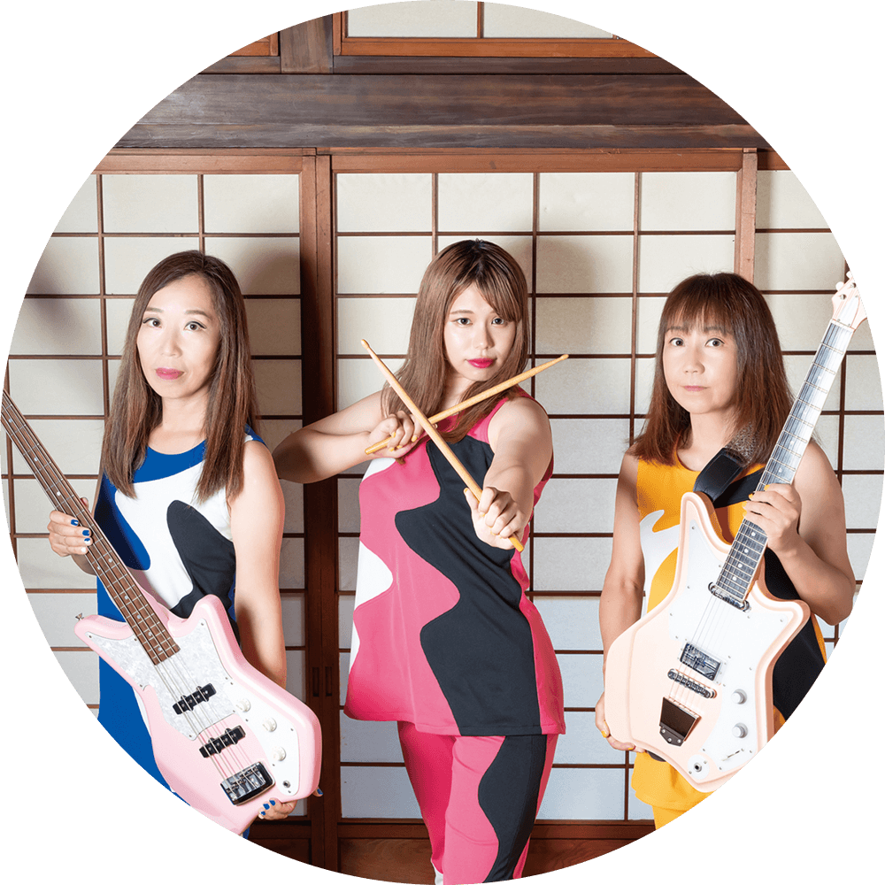 Shonen Knife holding their guitars and drum sticks in a Japanese setting